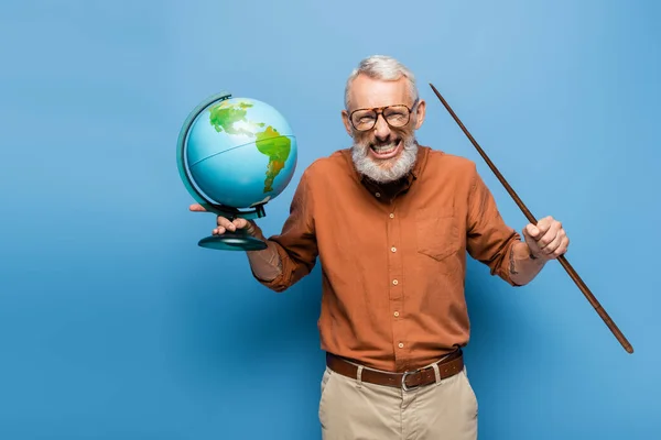 Excited middle aged teacher in glasses holding pointer stick and globe on blue — Stock Photo