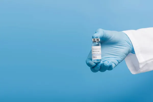 Cropped view of doctor in latex glove holding vial with coronavirus vaccine isolated on blue — Stock Photo