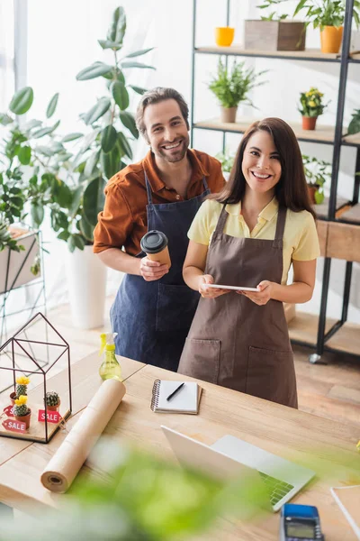 Floristen mit Pappbecher und digitalem Tablet blicken in Blumenladen auf Kamera — Stockfoto