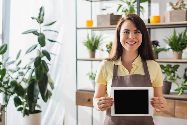 Positive florist holding digital tablet in flower shop — Stock Photo