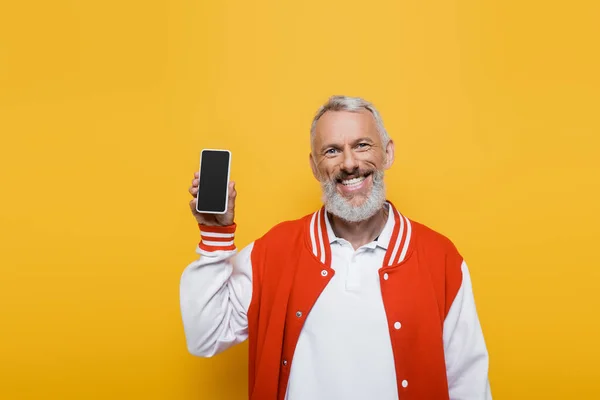 Homem positivo e maduro segurando celular com tela em branco isolado no amarelo — Fotografia de Stock