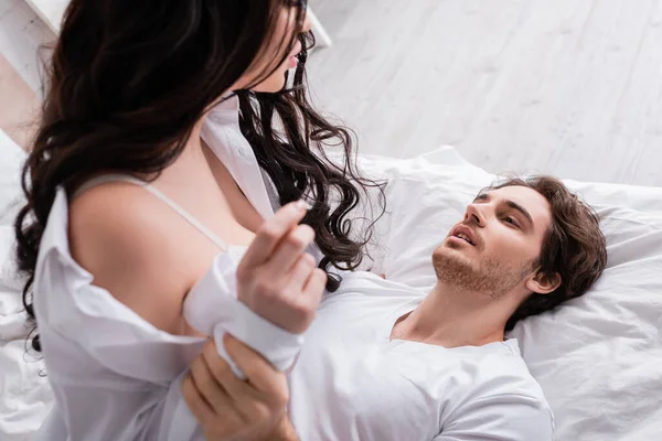 Brune floue femme séduire jeune homme couché sur le lit — Photo de stock