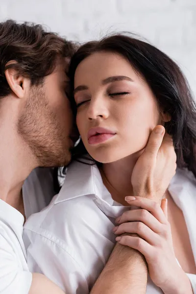 Sensual brunette woman with closed eyes near man embracing and kissing her in morning — Stock Photo