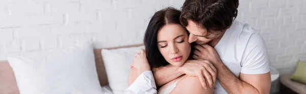 Young man hugging sensual brunette woman in bedroom, banner — Stock Photo