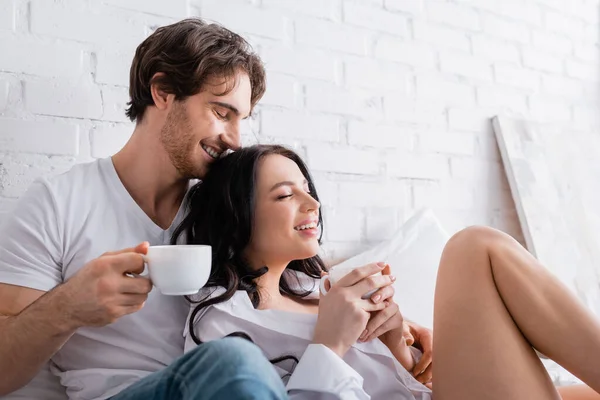 Felice uomo e donna seducente con gli occhi chiusi bere caffè del mattino in camera da letto — Foto stock