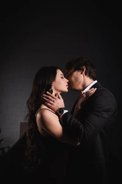 Passionate couple in elegant clothes kissing at night in bedroom — Stock Photo