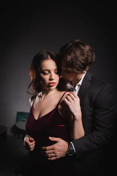 Молодий чоловік спокушає красиву молоду жінку в елегантній сукні в спальні вночі — стокове фото