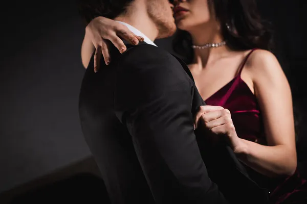 Vista ritagliata di donna elegante sfocata abbracciando l'uomo in giacca e cravatta di notte — Foto stock