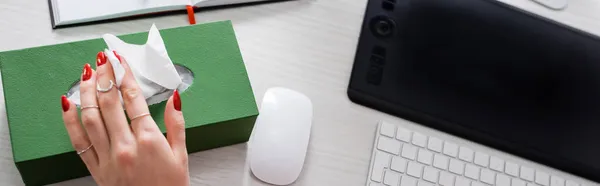 Vista recortada de la mujer enferma tomando servilleta de papel cerca de la tableta gráfica, ratón de la computadora y el teclado en el escritorio, bandera - foto de stock