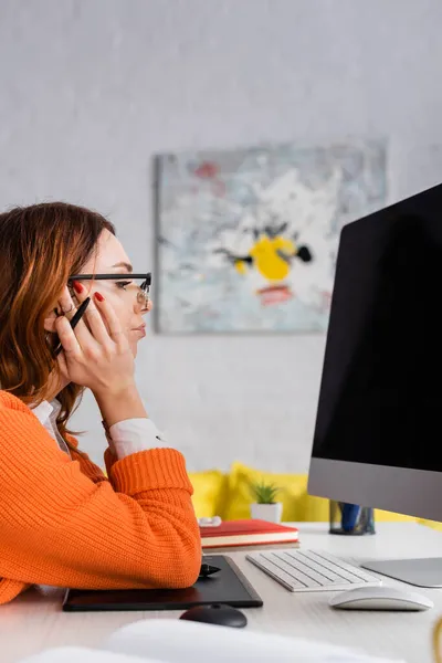 Seitenansicht des durchdachten Retuschierers in Brille, der bei der Arbeit zu Hause auf den Monitor schaut — Stockfoto