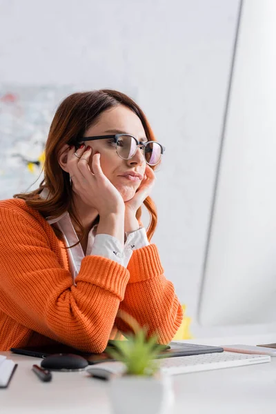 Displeased freelancer in eyeglasses working near blurred monitor and graphic tablet — Stock Photo