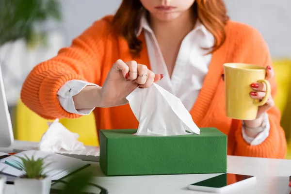 Vue partielle de la femme malade floue avec tasse de thé prise serviette en papier de l'emballage — Photo de stock