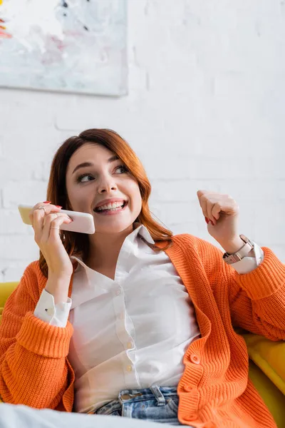 Excited woman sending voice message on mobile phone while sitting at home — Stock Photo