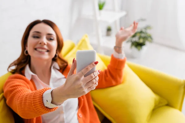 Mulher desfocada sorrindo e gesticulando enquanto toma selfie no celular — Fotografia de Stock