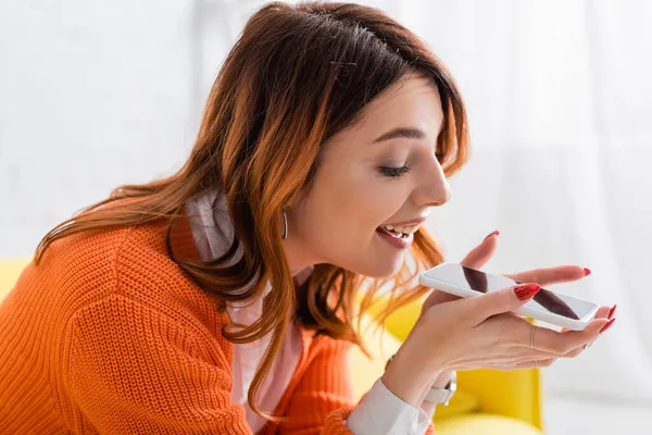 Femme joyeuse envoyer un message vocal sur un téléphone mobile avec écran blanc à la maison — Photo de stock