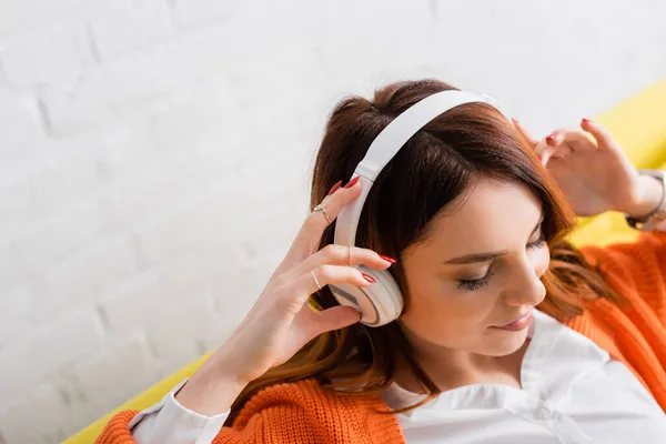 Visão de alto ângulo da jovem mulher satisfeita com olhos fechados ouvindo música em fones de ouvido — Fotografia de Stock