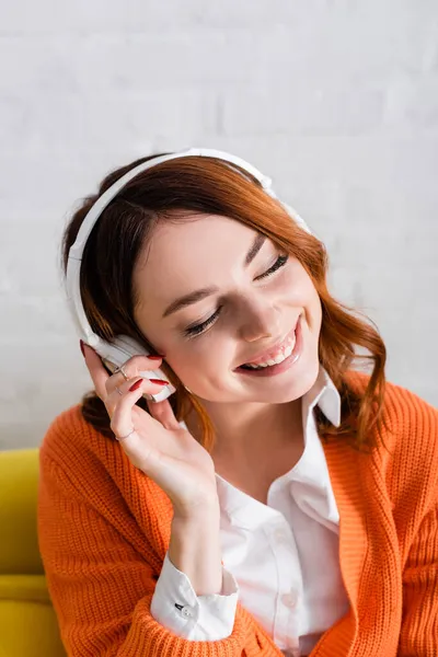 Young woman with closed eyes smiling while listening music in wireless headphones — Stock Photo