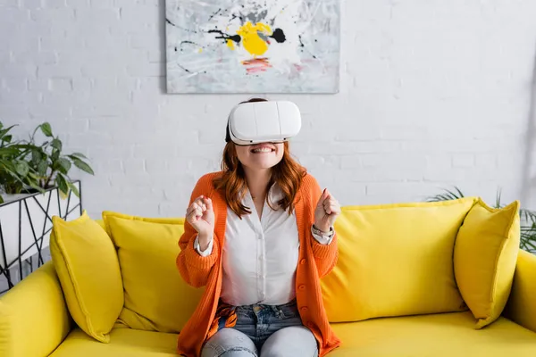 Excited woman with clenched fists gaming in vr headset on sofa at home — Stock Photo