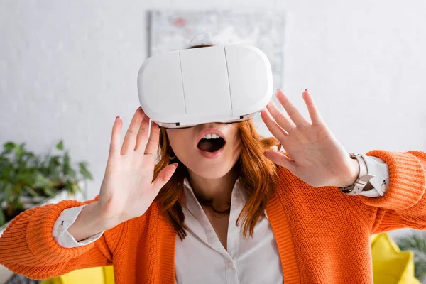 Mujer sorprendida con la boca abierta gesto mientras que los juegos en auriculares vr en casa - foto de stock