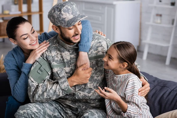 Positive family sitting near man in military uniform on couch — Stock Photo