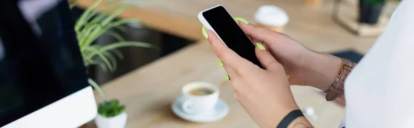 Vista recortada de mujer de negocios tatuada usando teléfono inteligente con pantalla en blanco, pancarta - foto de stock