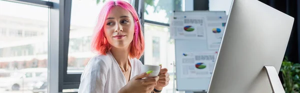 Happy young businesswoman with pink hair holding cup of coffee in office, banner — Stock Photo