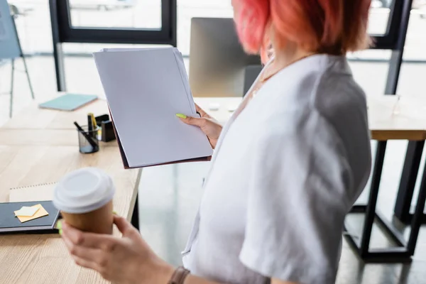 Cropped view of blurred manager with pink hair holding coffee to go and blank papers — Stock Photo