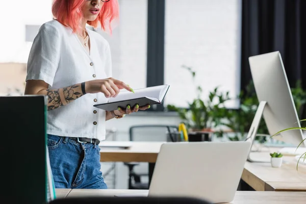 Visão cortada de jovem empresária com cabelo rosa apontando com o dedo no notebook — Fotografia de Stock