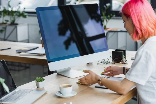 Pierced businesswoman with pink hair looking at computer keyboard — Stock Photo
