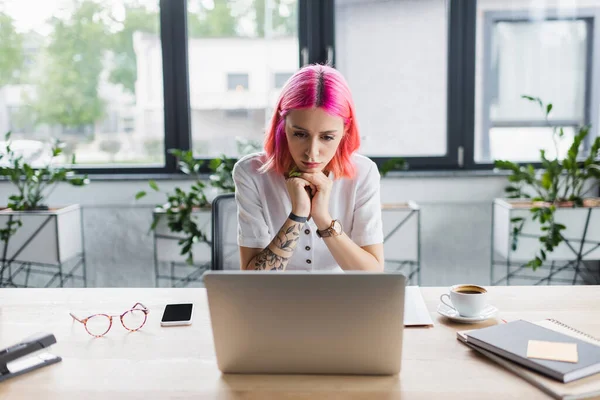 Fokussierte Geschäftsfrau mit rosa Haaren schaut im Büro auf Laptop — Stockfoto