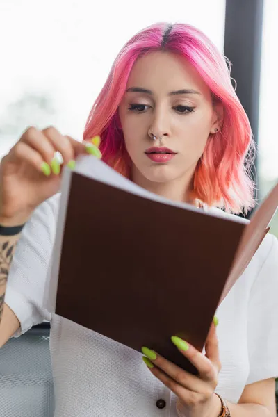 Femme d'affaires concentrée avec dossier de tenue de cheveux roses au bureau — Photo de stock