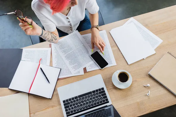 Vue du haut du gestionnaire avec les cheveux roses tenant des lunettes près des documents et des gadgets sur le bureau — Photo de stock