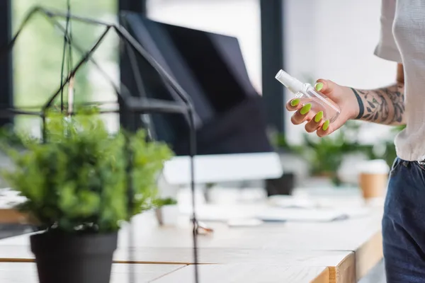 Vue recadrée du gestionnaire tatoué tenant bouteille avec désinfectant dans le bureau — Photo de stock