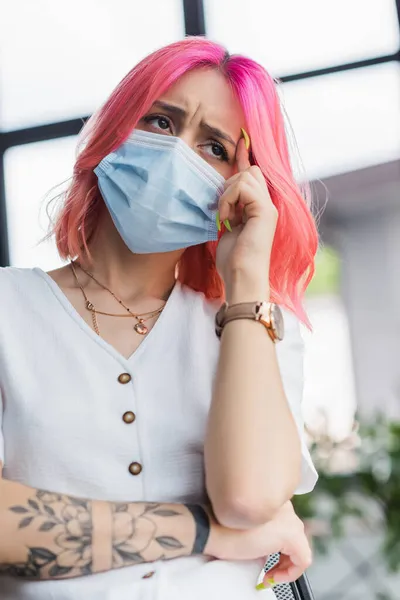 Mulher de negócios cansada com cabelo rosa na máscara médica com dor de cabeça no escritório — Fotografia de Stock