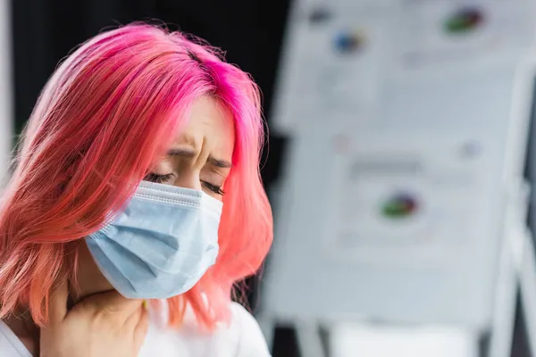 Donna malata con capelli rosa in maschera medica che ha mal di gola in ufficio — Foto stock
