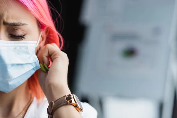 Vista ritagliata di triste giovane manager con i capelli rosa indossando maschera medica in ufficio — Foto stock
