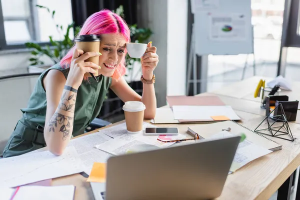 Mulher de negócios preocupado com cabelo rosa segurando café e olhando para laptop — Fotografia de Stock