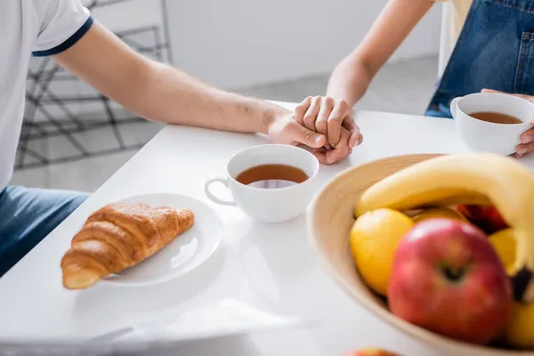 Cropped view of couple holding hands during breakfast — Stock Photo