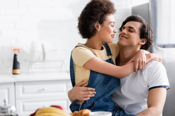 Felice donna afro-americana che abbraccia il fidanzato in cucina — Foto stock