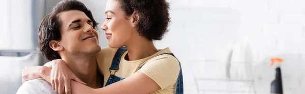 Happy african american woman hugging boyfriend in kitchen, banner — Stock Photo