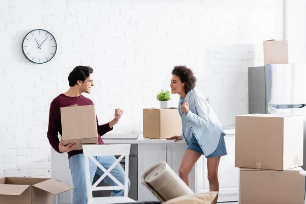 Excité couple interracial célébrant la relocalisation près de boîtes en carton — Photo de stock