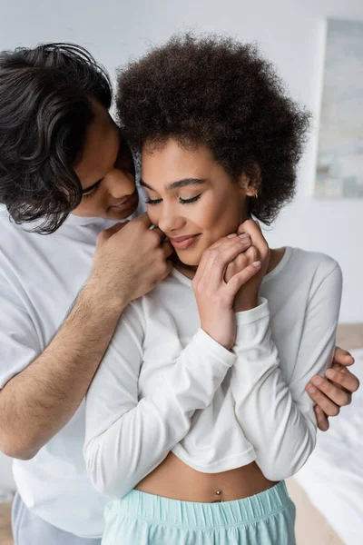 Junger Mann berührt lächelnde afrikanisch-amerikanische Freundin zu Hause — Stockfoto