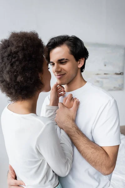 Junger Mann lächelt, während er die afrikanisch-amerikanische Freundin zu Hause ansieht — Stockfoto