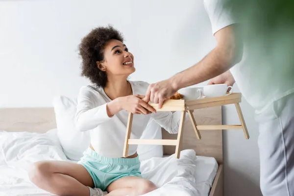 Felice donna afro-americana prendendo vassoio per la colazione vicino fidanzato — Foto stock