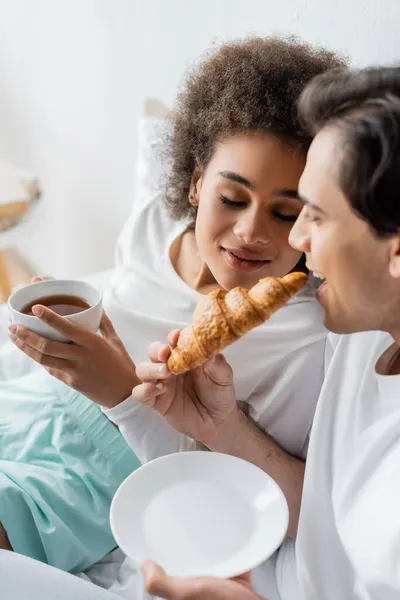 Gioiosa interrazziale coppia avendo colazione a letto — Foto stock