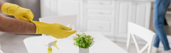 Cropped view of man wearing yellow rubber gloves with blurred woman on background, banner — Stock Photo