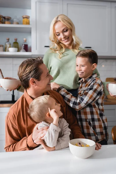 Happy family looking at mother during breakfast in kitchen — Stock Photo