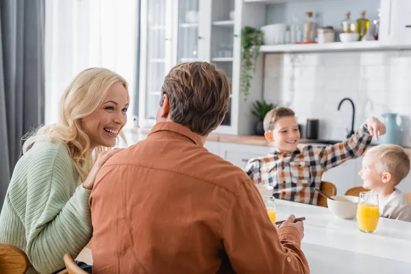 Blurred boy painting at brother while having breakfast with parents in kitchen — Stock Photo