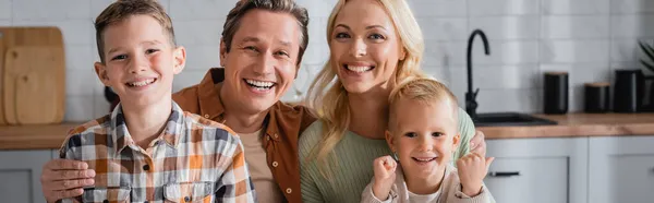 Happy parents and sons smiling at camera at home in kitchen, banner — Stock Photo