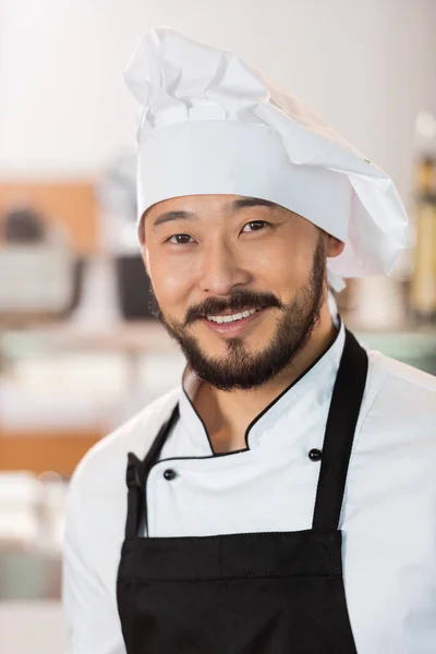 Retrato de sorrindo asiático chef olhando para câmera na cozinha — Fotografia de Stock